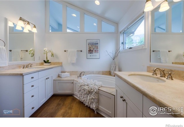 bathroom featuring lofted ceiling, two vanities, a sink, and wood finished floors