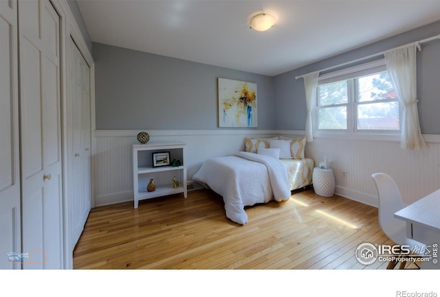 bedroom featuring light wood-style flooring, a closet, and wainscoting