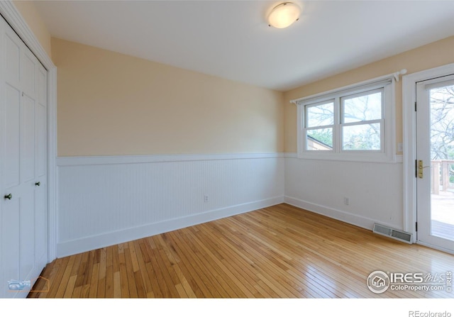 spare room featuring a wealth of natural light, wainscoting, and visible vents