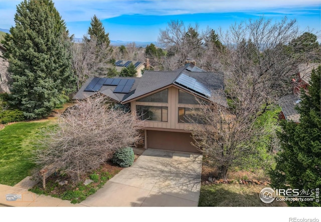 view of front of house with an attached garage, roof mounted solar panels, and concrete driveway