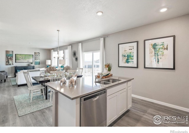 kitchen featuring sink, dishwasher, white cabinetry, hanging light fixtures, and an island with sink