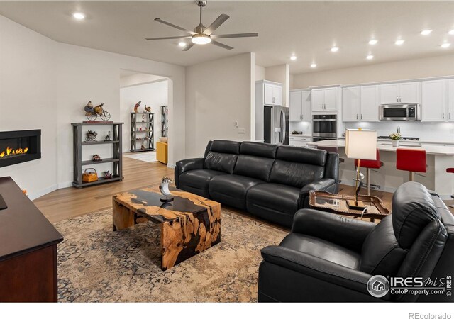 living room with light hardwood / wood-style flooring and ceiling fan