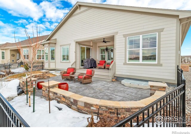 snow covered back of property with a patio, ceiling fan, and an outdoor fire pit