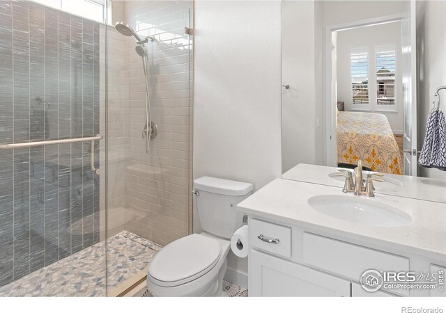 bathroom featuring vanity, a shower with shower door, and toilet