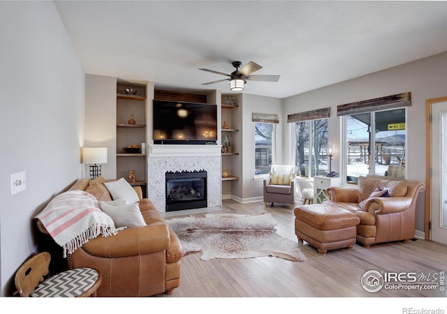 living room with a tile fireplace, light hardwood / wood-style floors, and ceiling fan