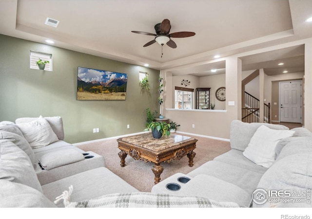 living room featuring a raised ceiling and light colored carpet