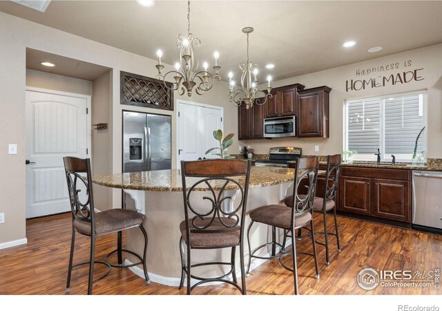 kitchen with light stone countertops, decorative light fixtures, stainless steel appliances, and a center island