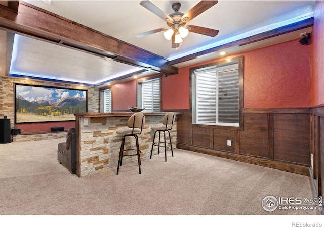 bar with light colored carpet, ceiling fan, and a tray ceiling