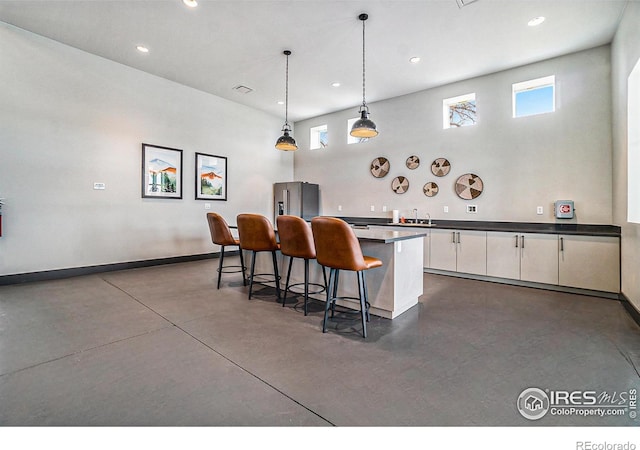 kitchen with sink, white cabinetry, decorative light fixtures, a center island, and a high ceiling