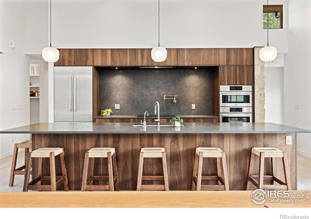 kitchen featuring hanging light fixtures, backsplash, stainless steel appliances, and a kitchen breakfast bar