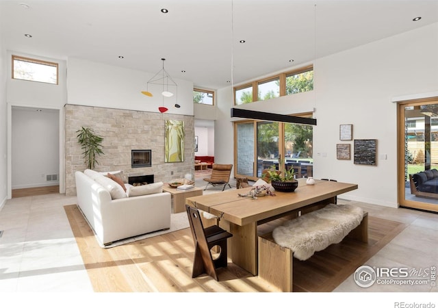 dining space with a towering ceiling and a stone fireplace