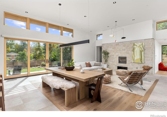 dining area with light wood finished floors, a high ceiling, and a fireplace