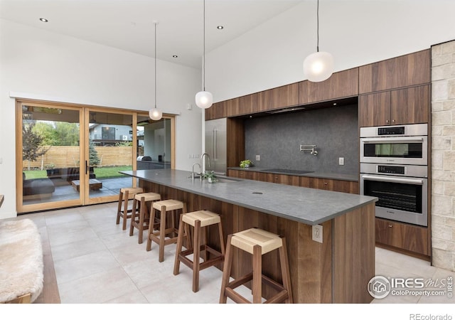 kitchen featuring double oven, dark countertops, a breakfast bar area, and modern cabinets