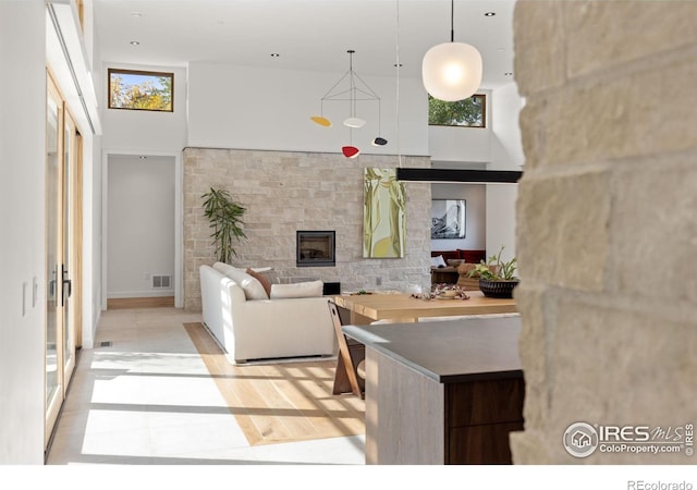 living room with a high ceiling, a fireplace, and visible vents