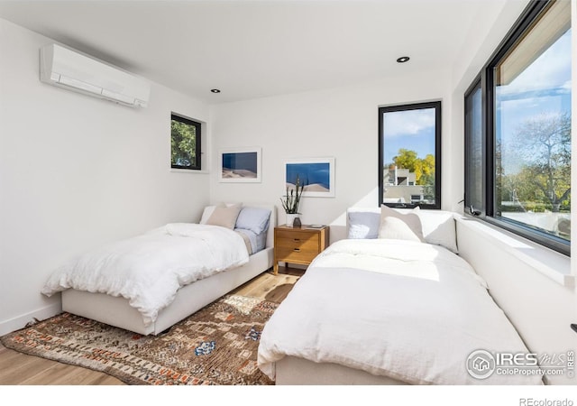 bedroom with wood-type flooring and a wall mounted AC