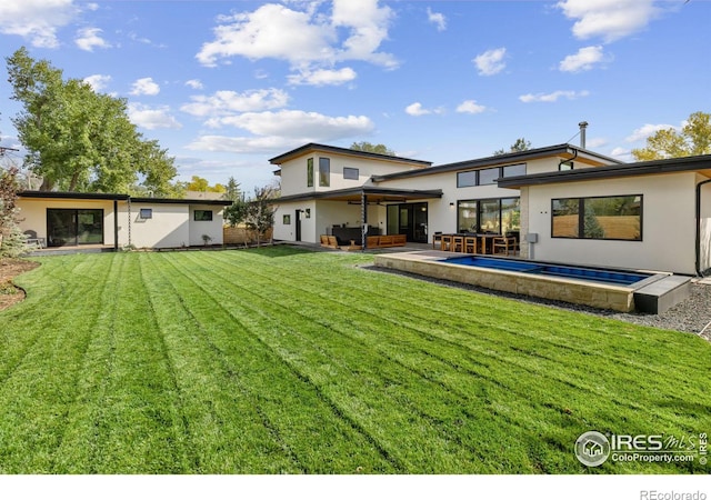 rear view of house with stucco siding, a patio area, an outdoor hangout area, and a yard