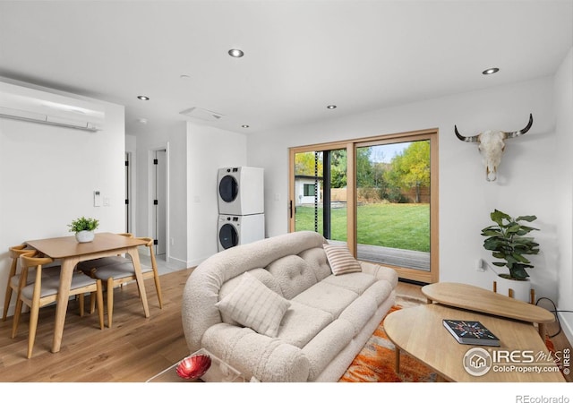 living room featuring stacked washer and dryer, light hardwood / wood-style floors, and an AC wall unit