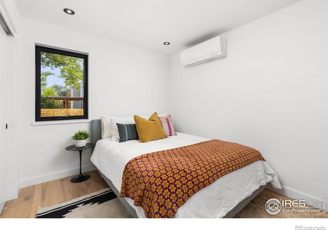 bedroom with a wall unit AC, recessed lighting, a closet, wood finished floors, and baseboards