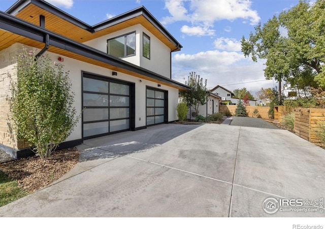 view of property exterior featuring a garage, driveway, fence, and stucco siding