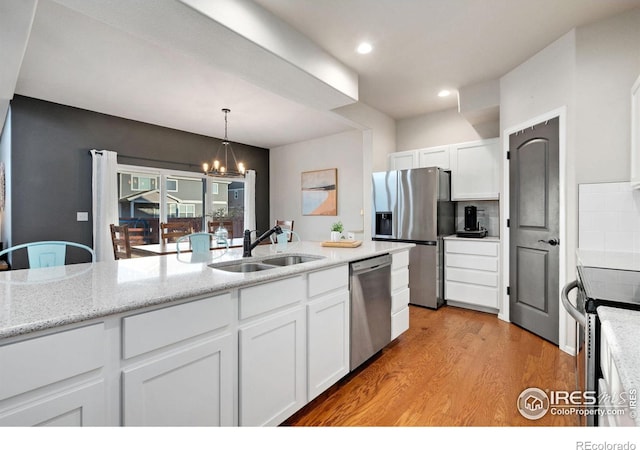 kitchen featuring sink, an inviting chandelier, stainless steel appliances, white cabinets, and light wood-type flooring