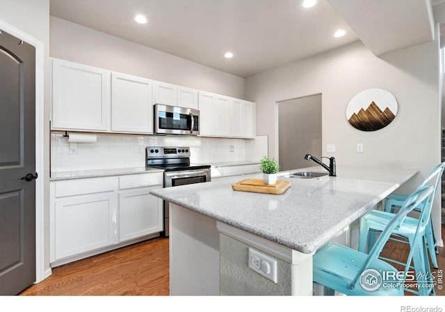 kitchen with sink, a breakfast bar area, appliances with stainless steel finishes, white cabinets, and kitchen peninsula