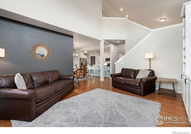 living room with a high ceiling, crown molding, hardwood / wood-style floors, and a notable chandelier