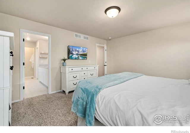 bedroom with ensuite bathroom and light carpet