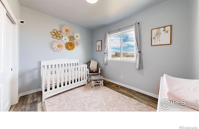 bedroom featuring hardwood / wood-style flooring, a nursery area, and a closet