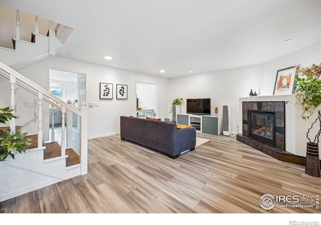 living room featuring a tiled fireplace and light hardwood / wood-style flooring