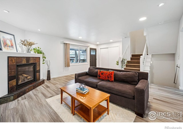 living room with a tile fireplace and light wood-type flooring