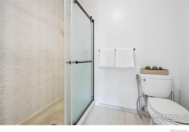 bathroom featuring a shower with shower door and toilet