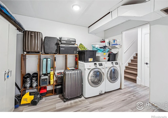 clothes washing area featuring washer and clothes dryer and light hardwood / wood-style flooring