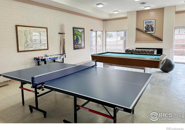 recreation room featuring brick wall and a textured ceiling