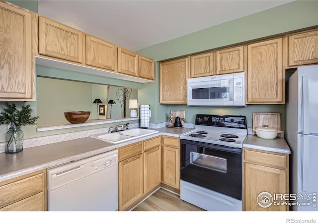 kitchen with sink, light brown cabinetry, and white appliances