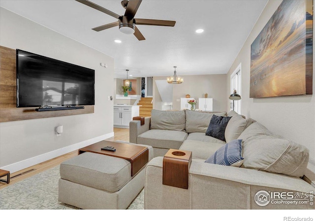 living room with ceiling fan with notable chandelier and light wood-type flooring