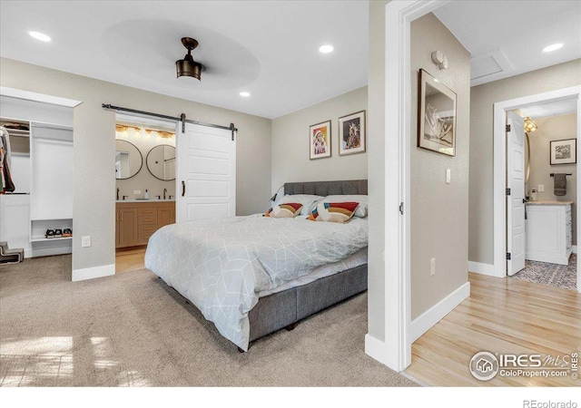 bedroom featuring ensuite bath, a barn door, sink, and a spacious closet