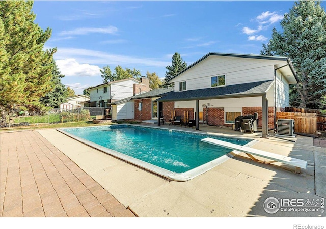 view of swimming pool with a patio, central AC, and a diving board