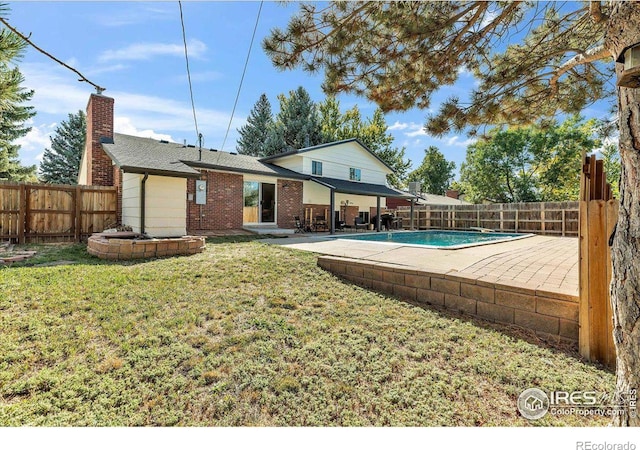 rear view of property with a fenced in pool, a patio, and a yard