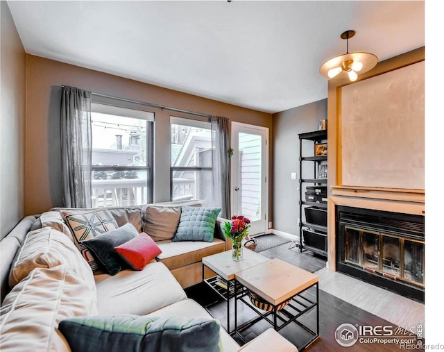 living room featuring wood finished floors, baseboards, and a fireplace with flush hearth