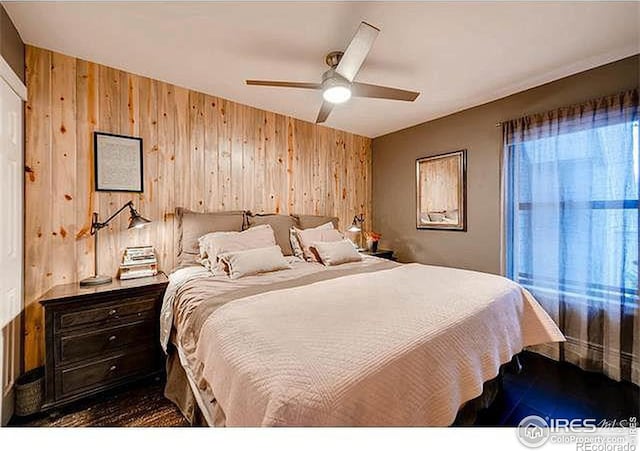 bedroom with wooden walls and ceiling fan
