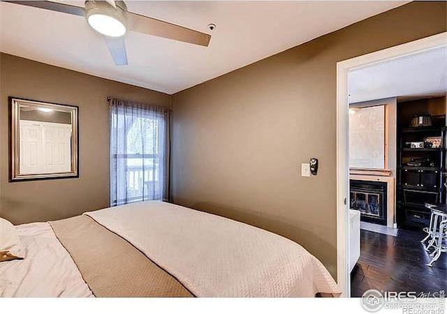 bedroom with a glass covered fireplace and a ceiling fan
