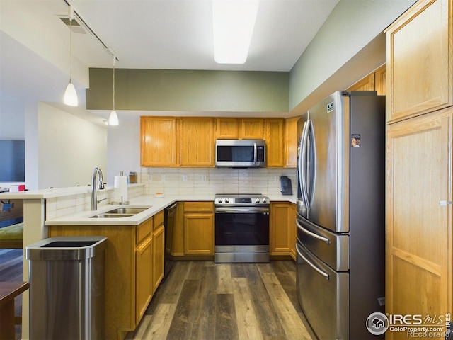 kitchen with sink, appliances with stainless steel finishes, tasteful backsplash, decorative light fixtures, and kitchen peninsula