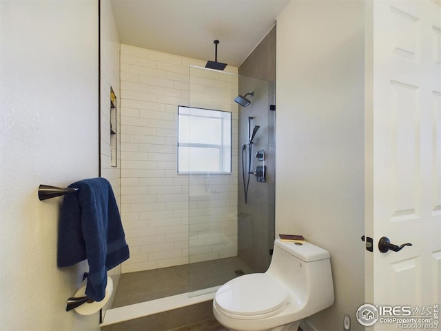 bathroom featuring tiled shower and toilet