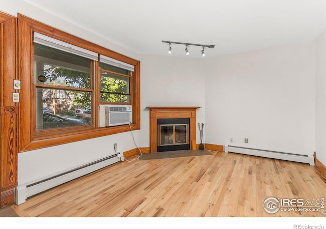 living room featuring a baseboard heating unit, cooling unit, track lighting, and light wood-type flooring