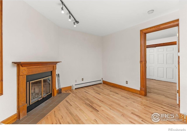 unfurnished living room featuring a baseboard radiator, wood-type flooring, and track lighting