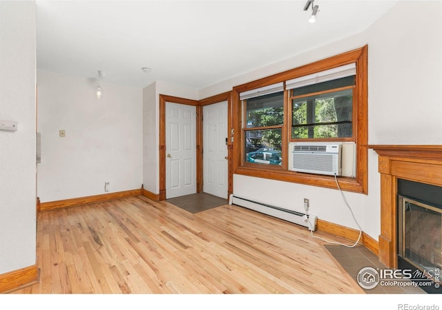 unfurnished living room with cooling unit, hardwood / wood-style flooring, and a baseboard heating unit