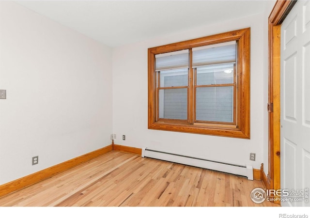 unfurnished room featuring a baseboard heating unit and light hardwood / wood-style floors