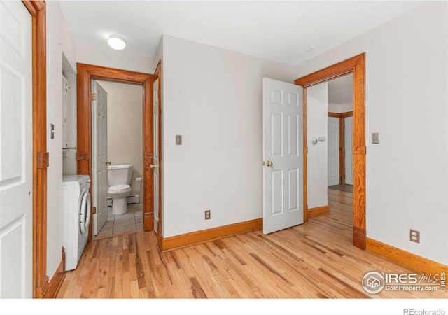 bedroom with ensuite bathroom, washer / dryer, and light hardwood / wood-style flooring