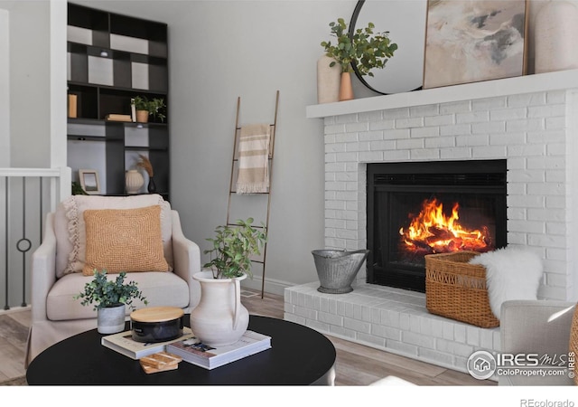 living area featuring a brick fireplace and wood-type flooring