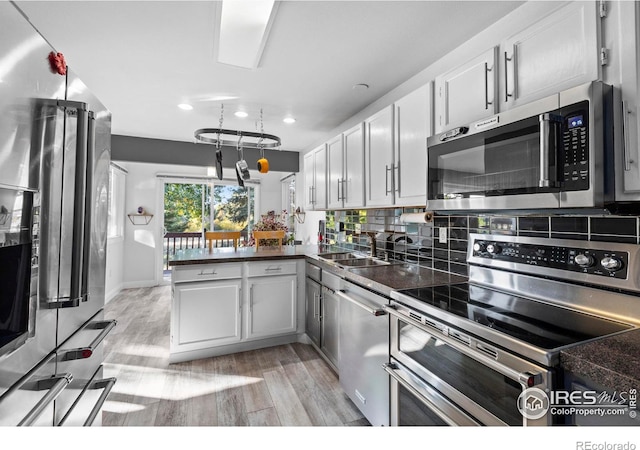 kitchen featuring stainless steel appliances, sink, white cabinets, and backsplash